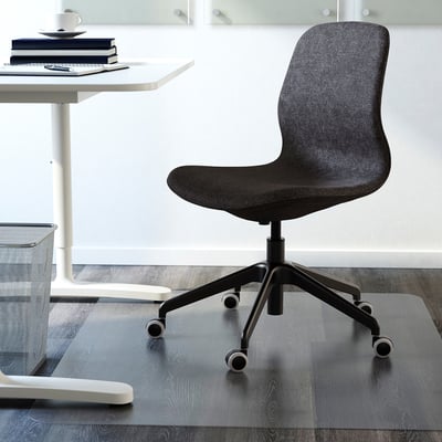 A modern office chair is placed near a white desk. The chair adjustable height and lumbar support for comfort.