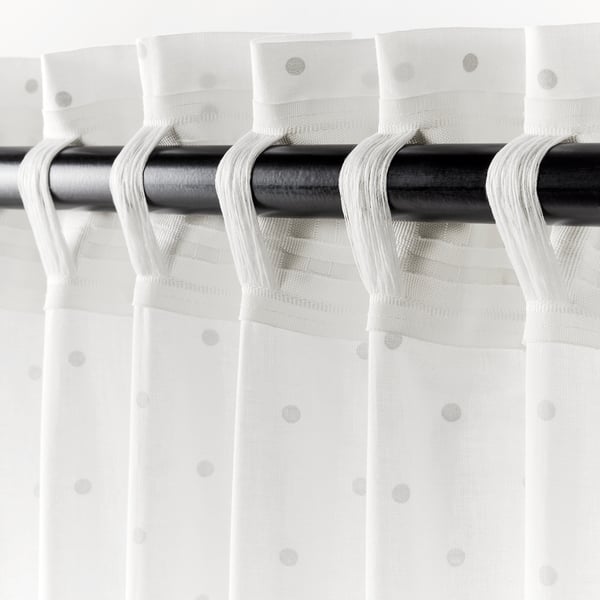 Black curtain rod holding three white curtains with looped tiebacks and small dots, displaying privacy and lightweight design.