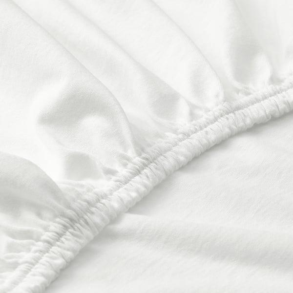 Close-up of elastic edge of white cotton sheet, showcasing smooth texture and secure stitching.