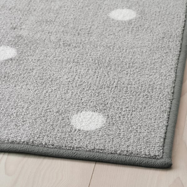 Modern grey rug with white dots on hardwood floor. Soft, durable, and non-slip, designed for kids comfort.
