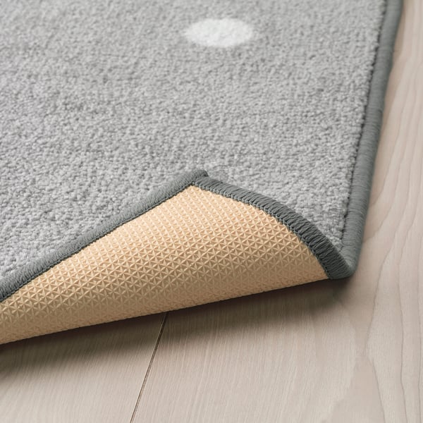 Grey rug with dots, non-slip backing for safety.