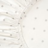 Close-up of high-quality white fitted sheet with gray polka dots. Elastic edges ensure secure fit.