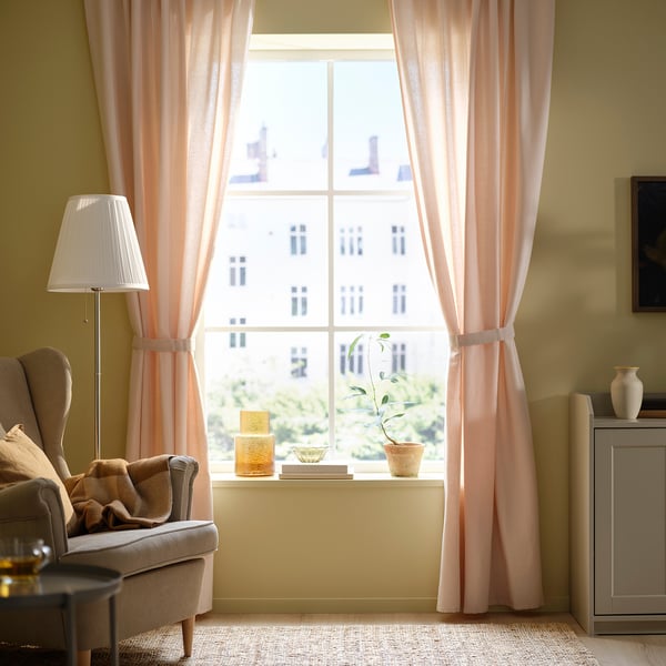 Bright room with LENDA light pink curtains, armchair, lamp, side table, and plant on windowsill.