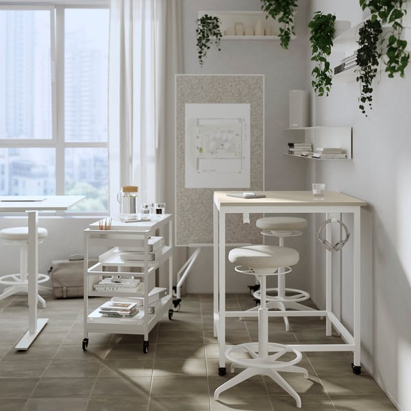 Modern office LIDKULLEN white sit-stand desks with adjustable stools, promoting active sitting. Bright, minimalist design with natural light.
