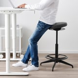 Person using sit/stand support cushion at office desk, promoting active sitting and posture improvement.