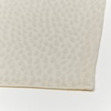Folded white tablecloth, intricate textured pattern, pristine quality.