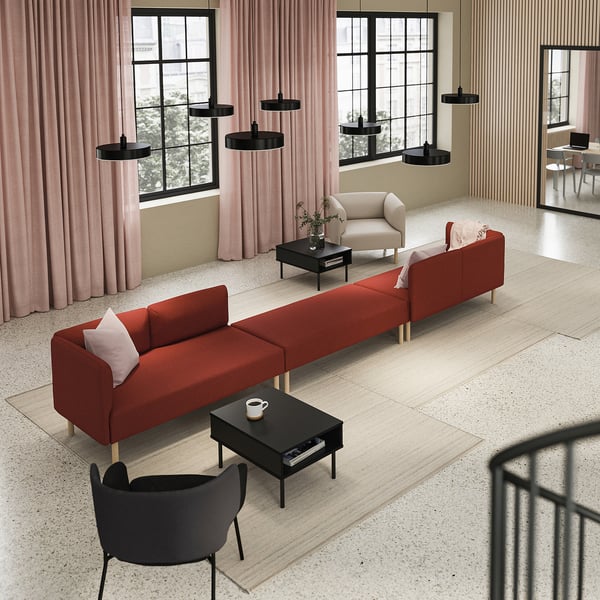 Minimalist living room with red sofa, black tables/chair, pink curtains, black lamps.