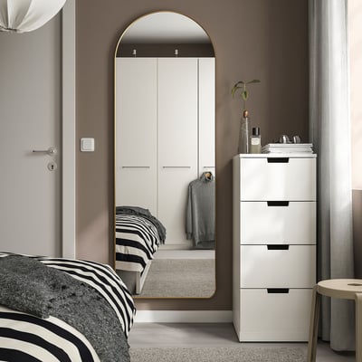 Modern bedroom with large arched LINDBYN mirror, gold-toned, minimalist decor.
