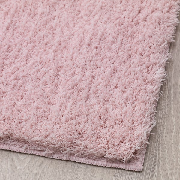 Soft, plush pink rug on a wooden floor, showing close-up texture and quality.