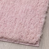 Soft, plush pink rug on a wooden floor, showing close-up texture and quality.