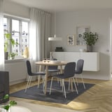 Modern dining set with round table and four dark grey chairs, perfectly fitting in a cozy corner.