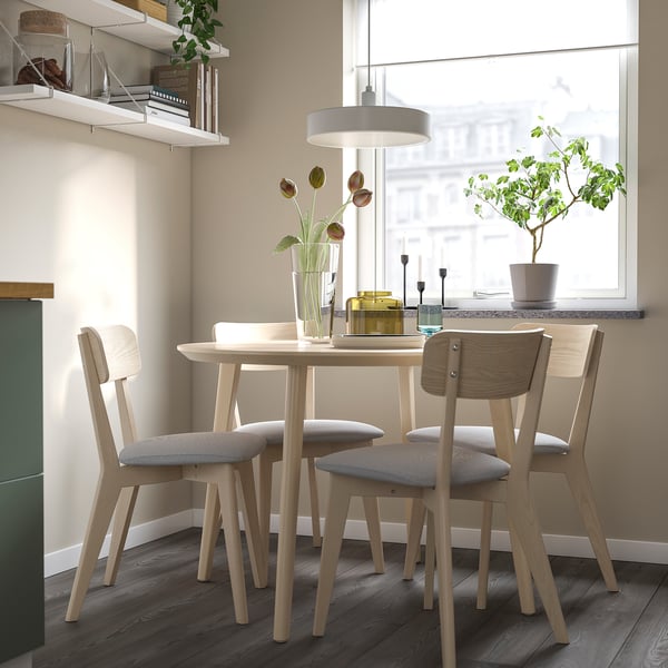 Light wood dining set, LISABO, fits cozily under large window. Modern, simple design with cushioned seats.