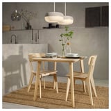 Natural wood dining set with light ash chairs and table, minimalist design, modern lighting above.