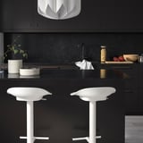 Modern kitchen with black glass countertops, bar stools, and decor.