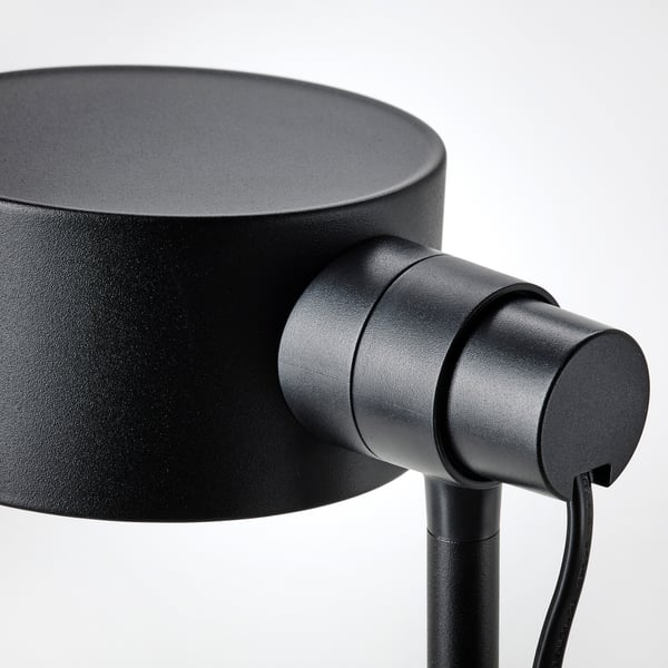 Black minimalist lamp with adjustable neck, mounted on a sleek stand.