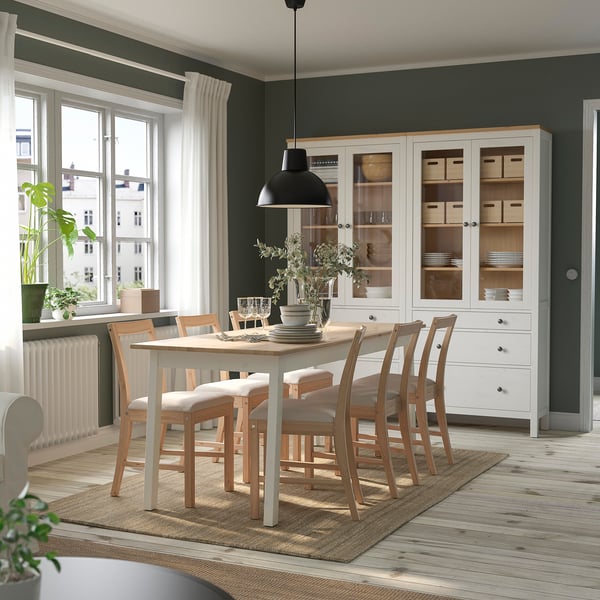 Dining room with LOHALS jute rug, white table, & chairs. Large window with curtains, white cabinet with dishes. Rug is durable & flat-woven.