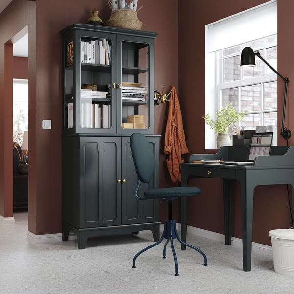 Modern home office with LOMMARP/BJÖRKBERGET desk, chair, and bookcase in dark gray, near a large window with a lamp and plants.