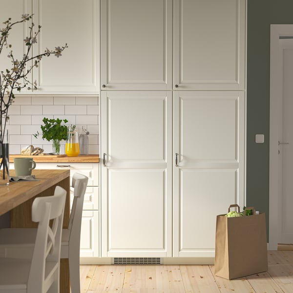 Modern kitchen with a large integrated white LUMNÄS fridge, wooden countertops, and white chairs. A paper bag sits nearby with groceries.