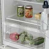 Fridge with adjustable glass shelves showing vegetables, water bottle, and jars; led lighting visible.