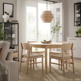 Modern dining set with LYDERSHOLM rug, light wood table & chairs, lamp, plant, storage.