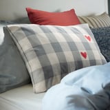 Checkered, grey-and-white pillow with red hearts, part of a set with varied colors and patterns.