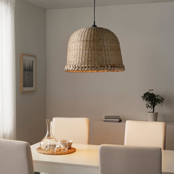 Large woven pendant lamp hangs over a dining table, casting soft light and creating a warm atmosphere.