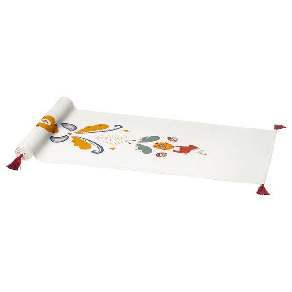 A white MÄVINN table runner with colorful, embroidered scandinavian patterns, featuring hearts and dala horses. It has tassels on either end.