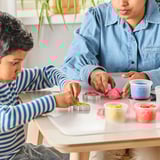 Two people playing with colorful modeling dough and cookie cutters.
