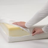 Person zips mattress protector onto white mattress.