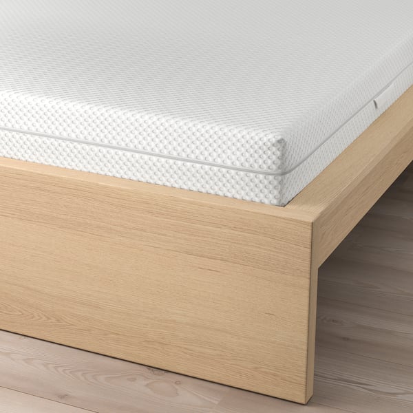 Image shows MALM bed with adjustable sides and a textured white mattress. It offers versatile positioning and support.