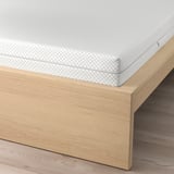 Image shows MALM bed with adjustable sides and a textured white mattress. It offers versatile positioning and support.