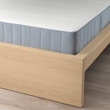 Close-up of MALM bed with light wood frame and blue-striped mattress, showing adjustable bed sides and supportive slats.