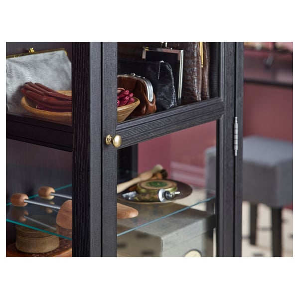 Black wooden cabinet with glass doors; displays various items on glass shelves.