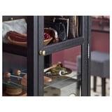 Black wooden cabinet with glass doors; displays various items on glass shelves.