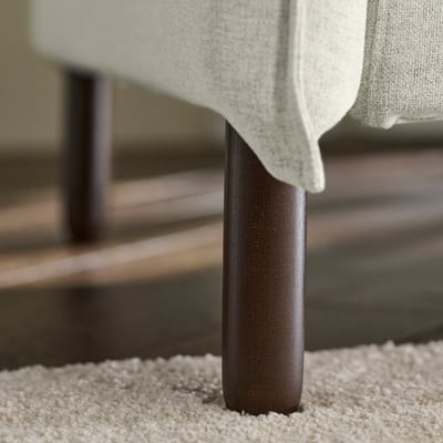 Light beige sofa with modern design, high backrest, and wooden legs; focus on soft cushions and cosy comfort.