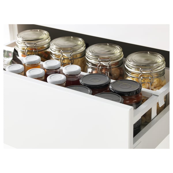 White kitchen drawer fully extended, holding multiple jars with lids, showcasing organized storage.
