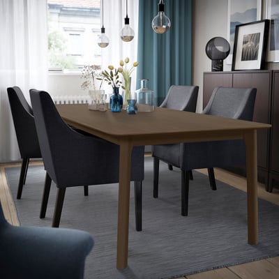 Modern oak dining set with four gray chairs, seating six, styled with vases and curtains.