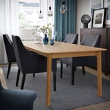 Oak veneer MELLANSEL extendable dining table with 6-10 seats, grey chairs, rug, and pendant lights.