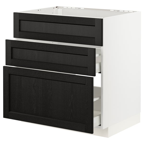 A white METOD kitchen cabinet with black stained wooden drawers. The drawers have beveled edges and are partially open, revealing the interior.