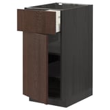 Brown wooden kitchen cabinet with open drawer, dark handles, vertical panels.