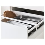 Kitchen drawer with adjustable compartments, showing metal tray and cork trivets; part of an organized storage system.