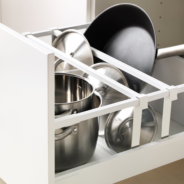 Organized pots and pans in a white kitchen cabinet drawer with dividers.