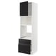 Modern white and black kitchen unit, consisting of high cabinet with open shelf, two drawers, and door in matte black with metallic handles.