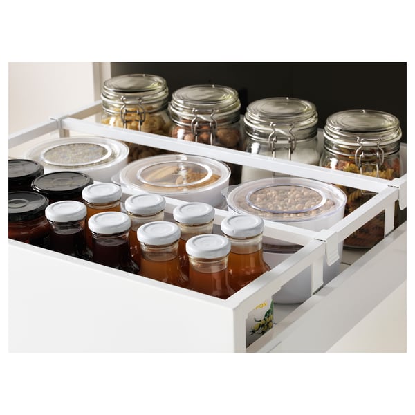 White kitchen drawer organizer with multiple compartments, storing various jars and containers.