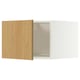 A white METOD kitchen cabinet with a light wood door slightly ajar. It a flat panel design and snap-on hinges.