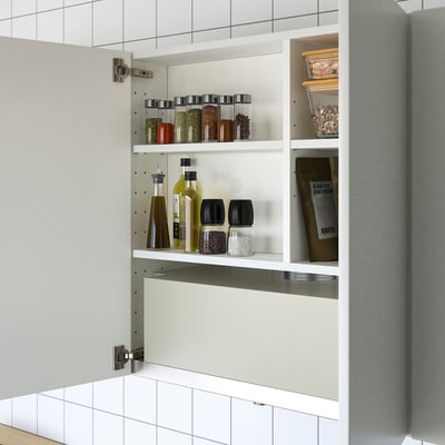 Open kitchen cabinet displaying storable items like spices, oils, and grains, illustrating its functional storage space.