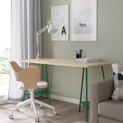 Green desk, white lamp, wood chair, grey sofa, art.