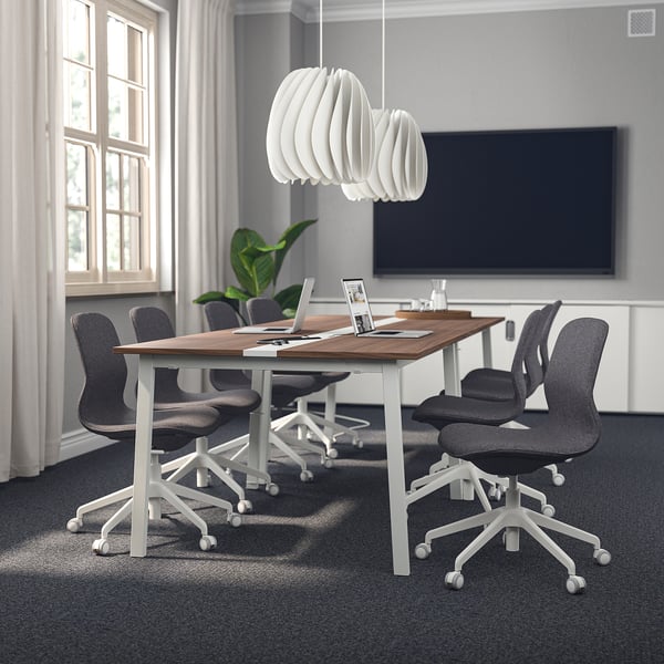 Modern conference room with MITTZON table, dark top, white legs, grey chairs, large tv, pendant light, and wide windows.