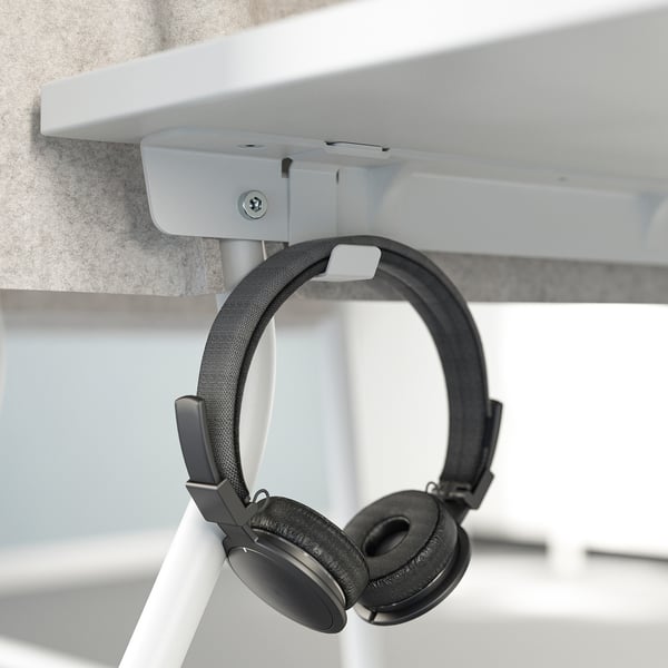 Black headphones hang from hook under white desk.