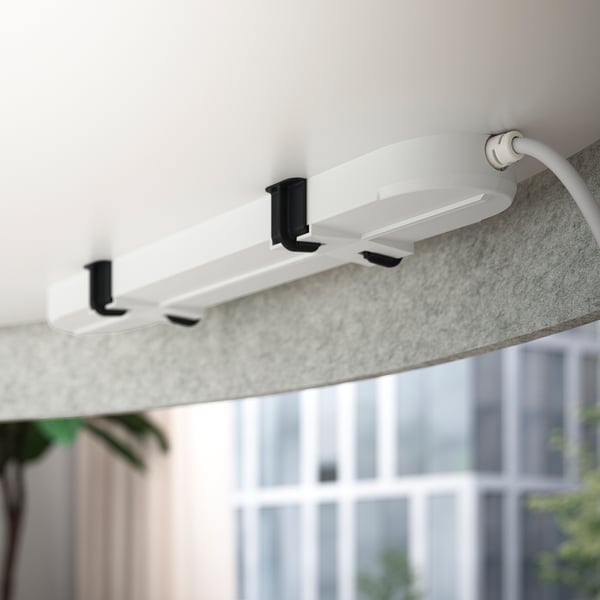 White MITTZON desk with hooks and cable, mounted under a table, offering a quiet workspace.